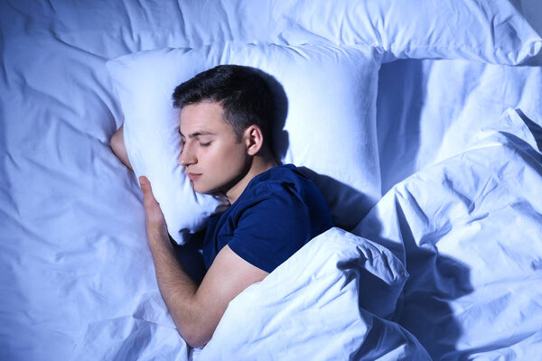 Young man sleeping in bed at night