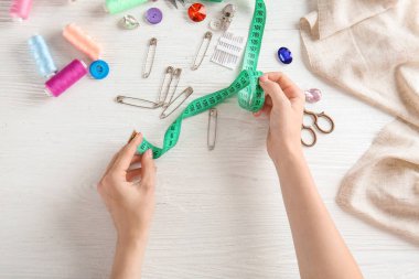 Beyaz arka planda ölçüm bandı ve aksesuarları ile kadın elleri
