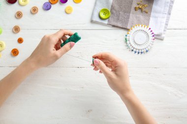 Dikme iplikleri ve hafif arka planda makara ile kadın eller