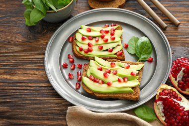 Ahşap masa üzerinde lezzetli avokado tost ile Plaka