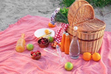 Plajda romantik piknik için lezzetli yiyecek ve içecek ile Wicker sepeti