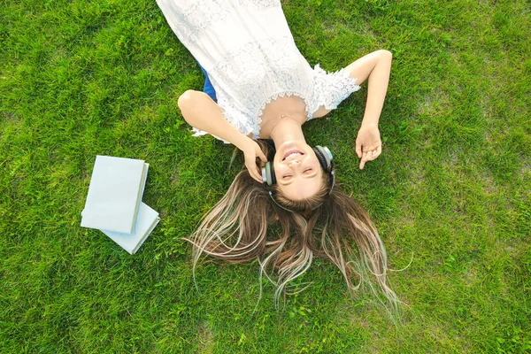 Beautiful young woman listening to audiobook in park — Stock Photo, Image