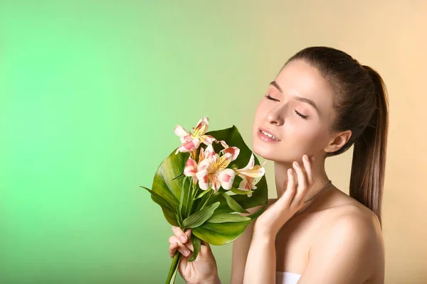 Belle jeune femme avec feuille tropicale et fleurs sur fond de couleur — Photo