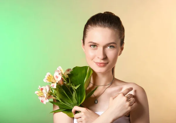 Vacker ung kvinna med tropiska blad och blommor på färg bakgrund — Stockfoto