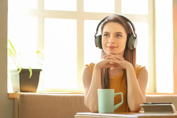 Όμορφη νεαρή γυναίκα ακούγοντας ηχητικό βιβλίο στο καφέ — Φωτογραφία Αρχείου
