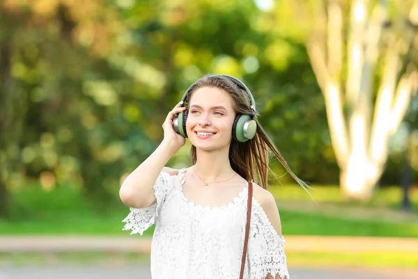 Beautiful young woman listening to audiobook in park — Stock Photo, Image