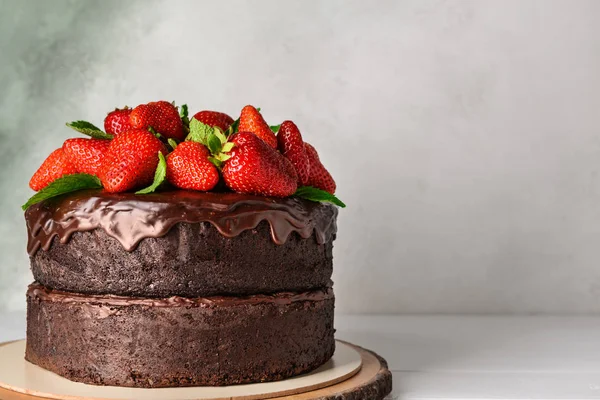 Tasty chocolate cake with strawberry on table against light background — Stock Photo, Image