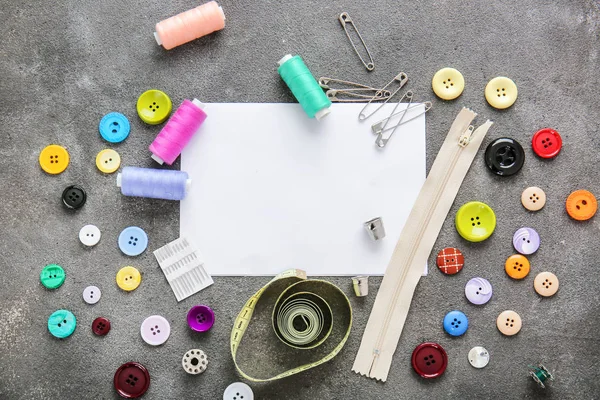 Set naaigarens met accessoires en vel papier op grijze achtergrond — Stockfoto