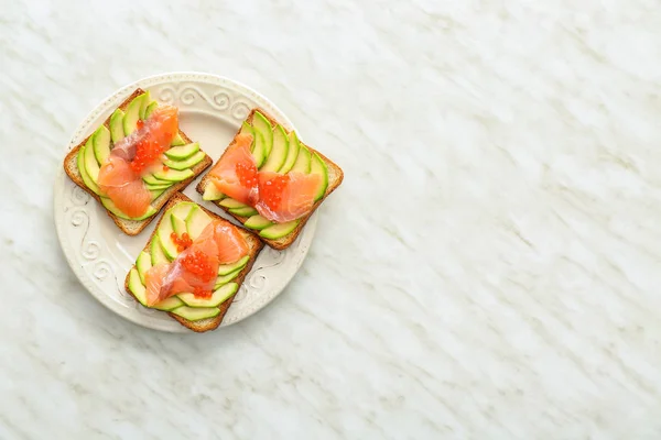 Plate with tasty avocado toasts on light table — Stock Photo, Image