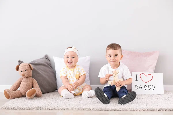 Petits enfants mignons avec carte de voeux pour la fête des pères près du mur de lumière — Photo