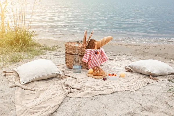 Weidenkorb mit leckerem Essen und Trinken für ein romantisches Picknick in Flussnähe — Stockfoto