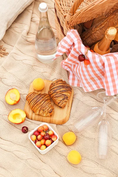 Смачні круасани, фрукти та напої для романтичного пікніка на плед — стокове фото
