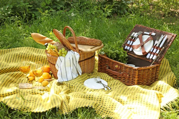 Canastas de mimbre con sabrosa comida y bebida para picnic romántico en el parque — Foto de Stock