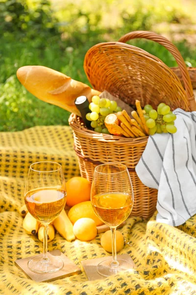 Wicker basket with tasty food and drink for romantic picnic in park