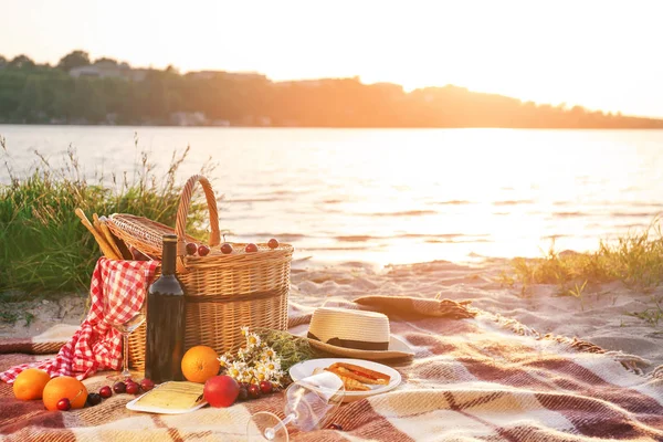 Cesto di vimini con cibi e bevande gustosi per un romantico picnic vicino al fiume — Foto Stock