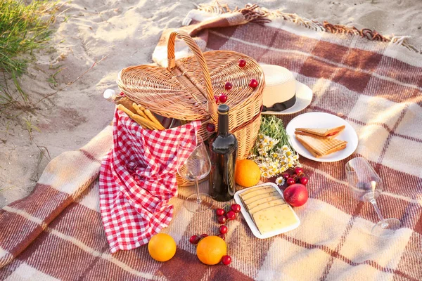 Cesto di vimini con cibi e bevande gustosi per un romantico picnic sulla spiaggia — Foto Stock