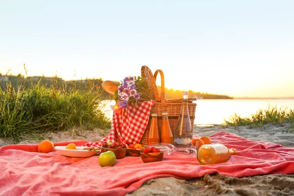 Cesto di vimini con cibi e bevande gustosi per un romantico picnic vicino al fiume — Foto Stock