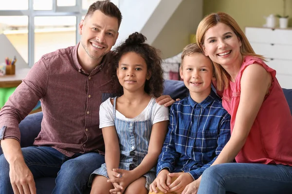 Pareja feliz con niños adoptivos en casa —  Fotos de Stock