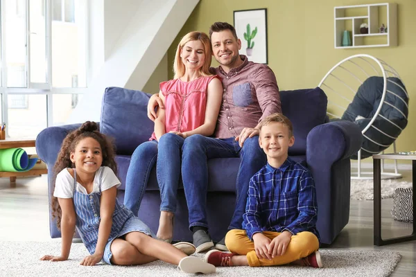 Glückliches Paar mit kleinen Adoptivkindern zu Hause — Stockfoto