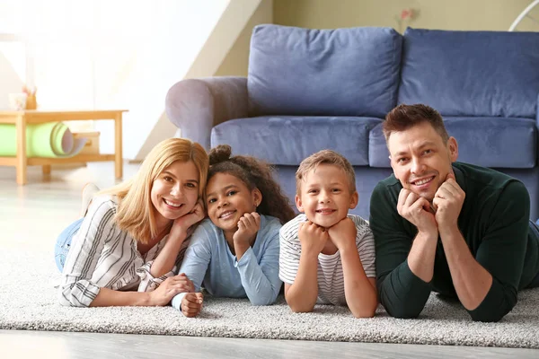 Glückliches Paar mit kleinen Adoptivkindern zu Hause — Stockfoto