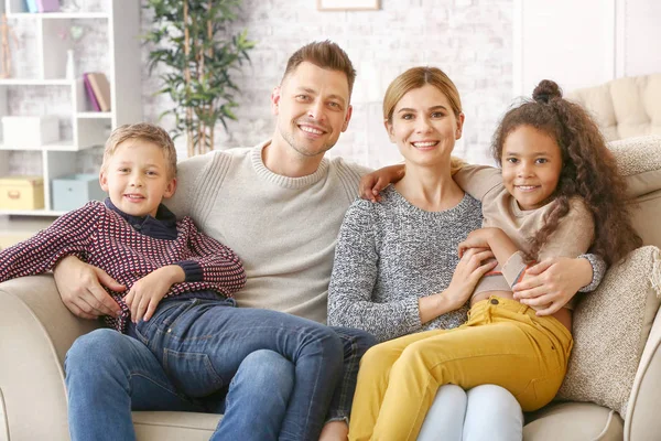 Glückliches Paar mit kleinen Adoptivkindern zu Hause — Stockfoto