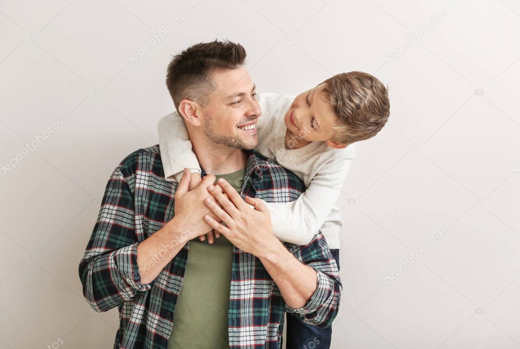 Happy man with little adopted boy on white background