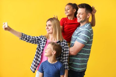 Küçük evlatlık çocukları ile mutlu çift renkli arka planda selfie alarak