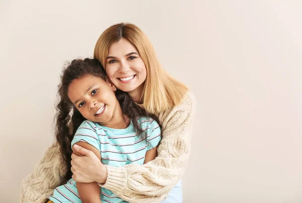 Mujer feliz con niña afroamericana poco adoptada sobre fondo blanco — Foto de Stock