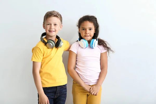 Lindos niños pequeños con auriculares sobre fondo claro —  Fotos de Stock