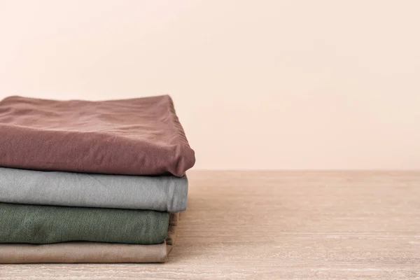 Stack of clean clothes on table against light background — Stock Photo, Image