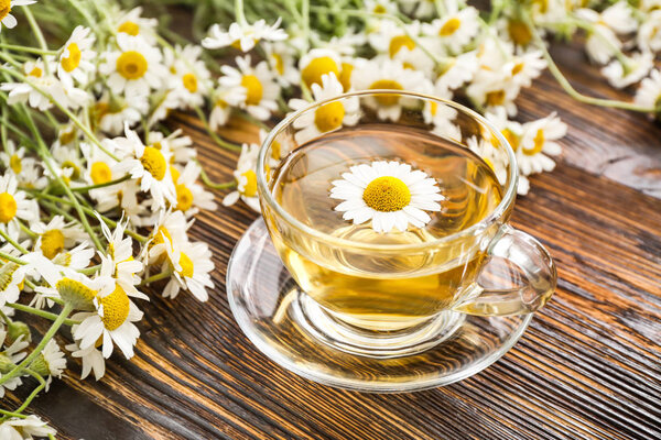 Cup of hot chamomile tea on wooden table