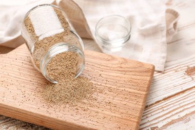 Ahşap masa üzerinde beyaz haşhaş tohumu ile devrik cam kavanoz