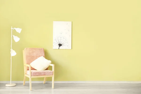 Comfortable armchair and lamp near color wall with picture — Stock Photo, Image