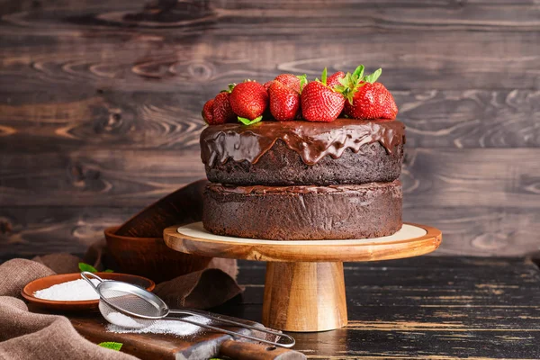 Stojak z pysznym ciastem czekoladowym na drewnianym stole — Zdjęcie stockowe