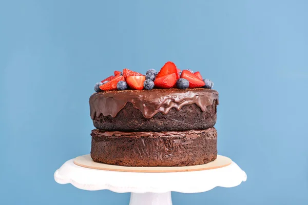 Stand con sabroso pastel de chocolate sobre fondo de color —  Fotos de Stock