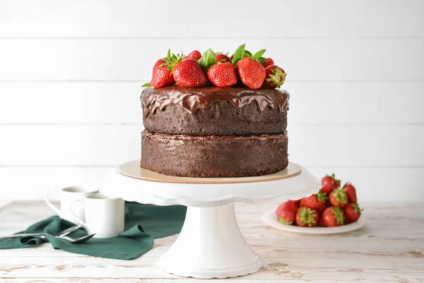 Stand with tasty chocolate cake on white wooden table — Stock Photo, Image