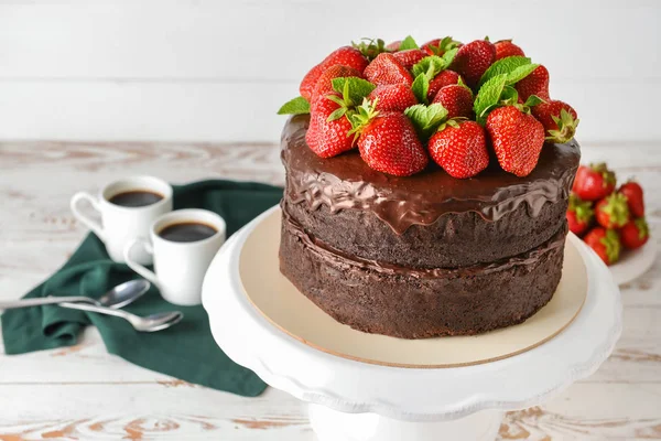 Stand com bolo de chocolate saboroso na mesa de madeira branca — Fotografia de Stock