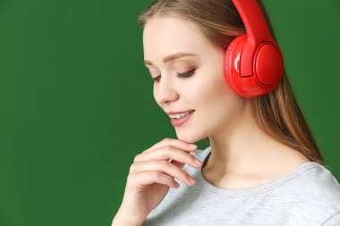 Renkli arka planda müzik dinleyen güzel genç bir kadın.