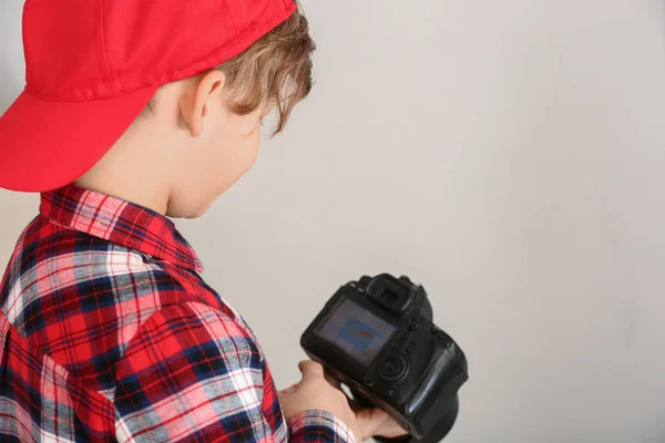 Cute little photographer with professional camera on light background — Stock Photo, Image