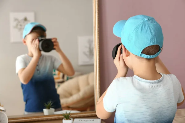 Милий маленький фотограф з професійною камерою біля дзеркала вдома — стокове фото