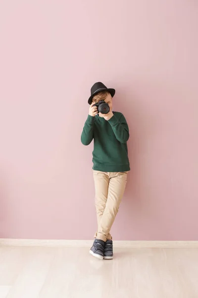 Cute little photographer with professional camera near color wall — Stock Photo, Image