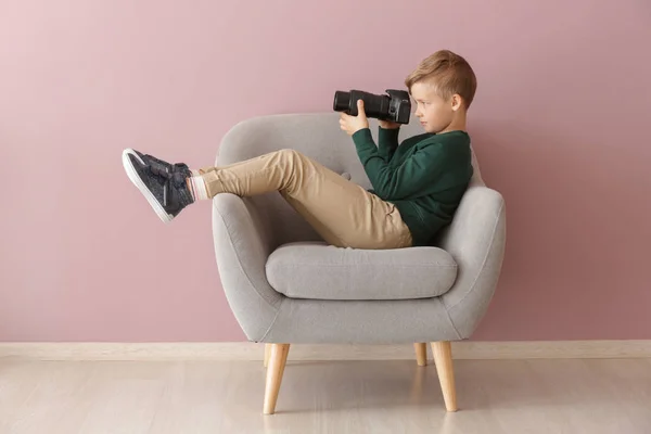 Aranyos kis fotós, professzionális kamera ül fotel beltérben — Stock Fotó