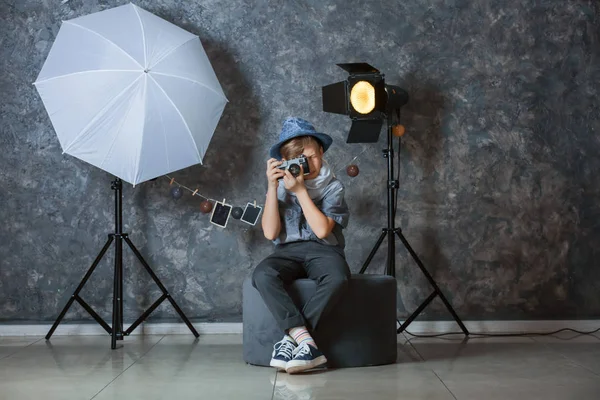 Cute little photographer with camera in professional studio