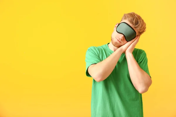 Sleepy man with mask on color background — Stock Photo, Image