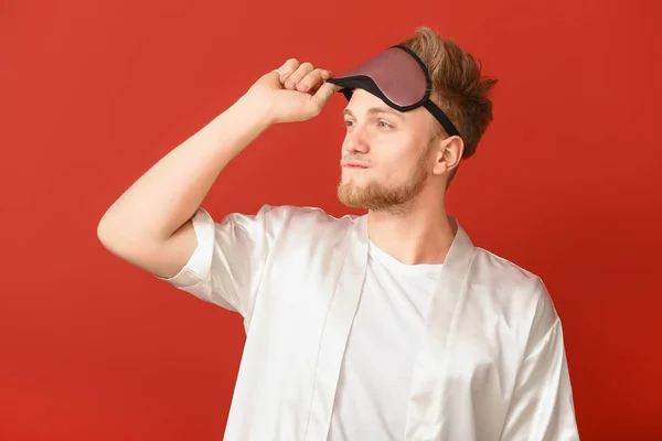 Happy young man with sleep mask on color background — Stock Photo, Image