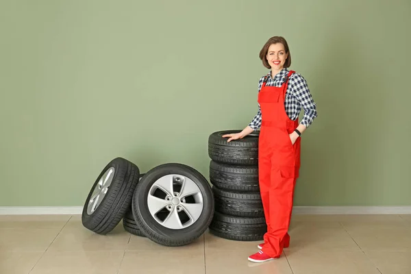 Młoda kobieta mechanik z opon samochodowych w pobliżu ściany kolorów — Zdjęcie stockowe