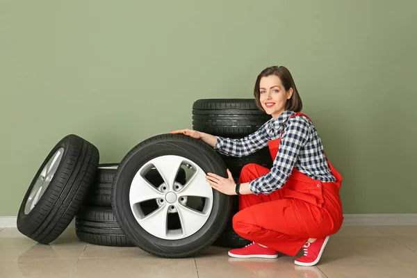 Молода жінка-механік з шинами автомобіля біля кольорової стіни — стокове фото