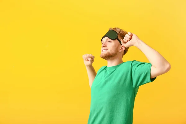 Sleepy man with mask on color background