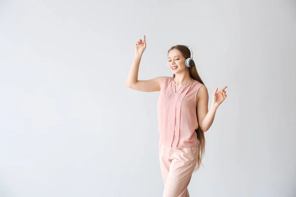 Hermosa joven escuchando música sobre fondo claro — Foto de Stock