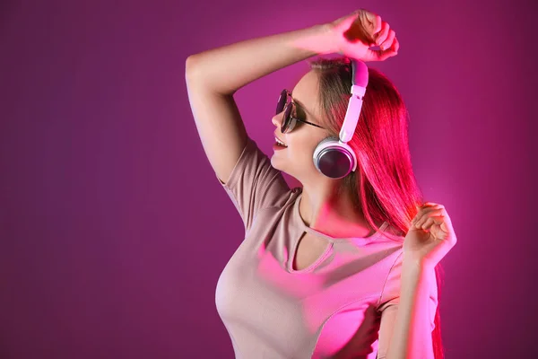 Piękna młoda kobieta słuchająca muzyki na kolorowym tle — Zdjęcie stockowe
